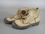 pair of tan boots with black soles sitting on a white surface