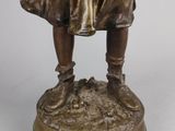 bronze statue of a boy holding a bird on a pedestal