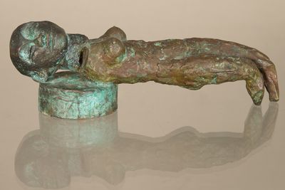 statue of a person laying on a table with a reflection on the surface