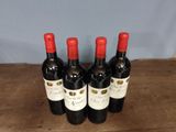 four bottles of wine are lined up on a wooden table