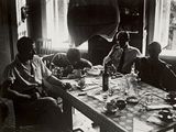 many people sitting around a table eating and drinking
