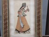 tableau représentant une femme tenant une cruche d'eau, dans un cadre en bois