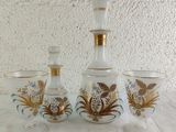 three glass vases and a decanter sitting on a table