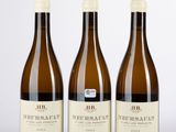 trois bouteilles de vin posées sur une table blanche