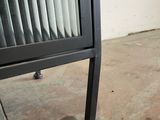 a black and white cat sitting on the floor next to a metal cabinet