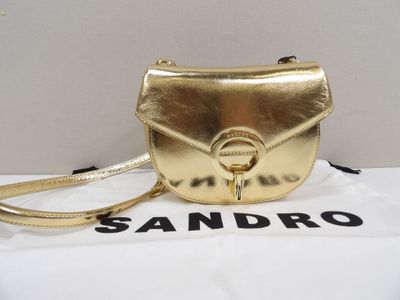 the gold handbag is sitting on top of a white box