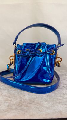 a blue bucket bag with a gold chain strap