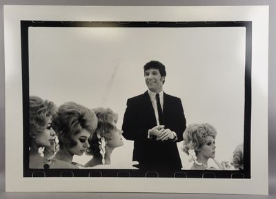 black and white photograph of a man in a suit standing in front of a group of women
