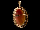 a close up of a gold pendant with a red stone in it