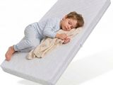 un bébé qui dort sur un matelas, recouvert d'une couverture