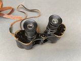 a pair of binoculars sitting on a table next to a leather strap