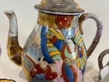a tea pot and four cups on a table
