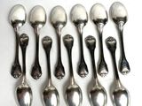 six silver spoons are lined up in a row on a white surface