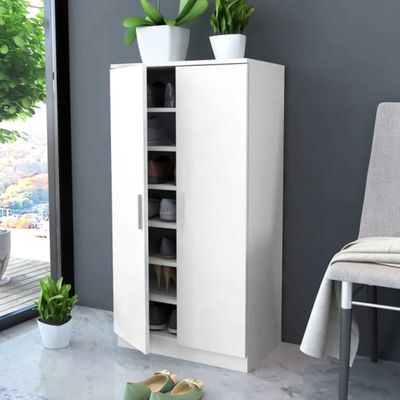 a white cabinet with shoes on the floor next to a chair