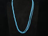 a necklace with a blue bead on a black mannequin