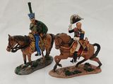 two figurines of two men on horses on a white surface