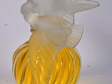 un vase en verre jaune surmonté d'un oiseau blanc