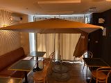 tables and chairs in a restaurant with an umbrella over them