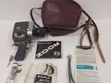 a brown bag, a camera, a book and other items laid out on a table