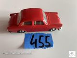 une petite voiture rouge posée sur une feuille de papier bleue