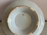 a white bowl with a gold rim on a marble table