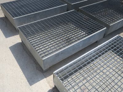 Plusieurs grilles en acier sont alignées sur un trottoir dans un parking