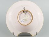 underside view of a white and yellow plate with a tag on it