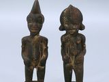 paire de figurines en bois représentant un homme et une femme, posées sur des socles en acrylique