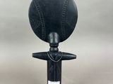 a black sculpture of a person holding a ball on top of a pole