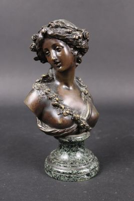 a bronze busturine of a woman with a flowered head