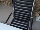 a black leather chair sitting in front of a white desk