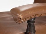 brown leather office chair with studded arms and foot rests against a white background