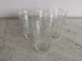 four clear glasses are lined up on a marble counter top