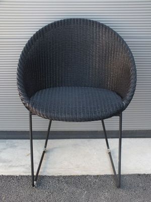 une chaise en osier noir avec une structure en métal noir