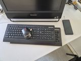 un écran d'ordinateur et un clavier posés sur un bureau, à côté d'un téléphone portable