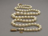 collier de perles avec un fermoir en or sur un fond gris
