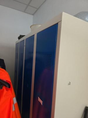 un homme vêtu d'une veste orange, debout devant un casier