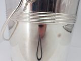 a silver bucket with a handle on a white table