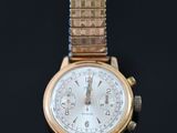 a gold watch with a white face on a black surface