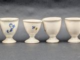 seven white vases lined up in a row on a table