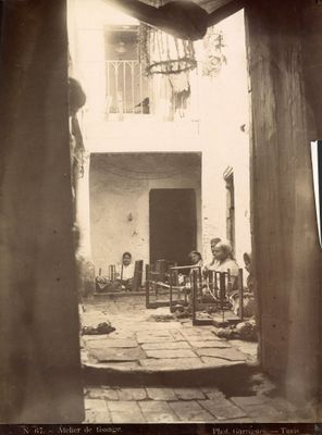 une photo en noir et blanc d'un homme assis dans une cour