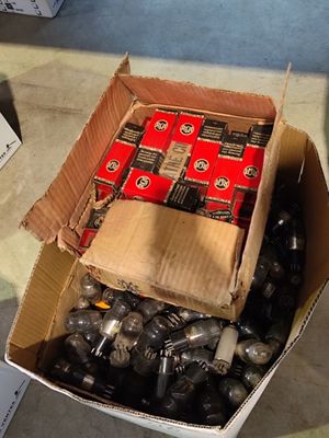 a cardboard box full of assorted batteries on the floor