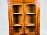 une vieille armoire en bois avec des portes vitrées, posée sur un parquet