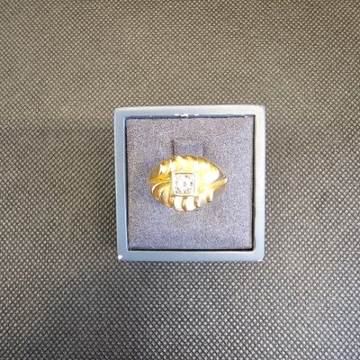 une bague en or dans une boîte blanche posée sur une surface grise