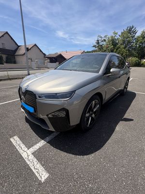 a silver bmw suv parked in a parking lot with houses in the background