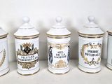 four white and gold canisters are lined up against a white wall