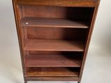une bibliothèque ancienne en bois, dotée d'un plateau en verre et d'étagères