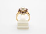 a close up of a gold ring with a pearl and garnets