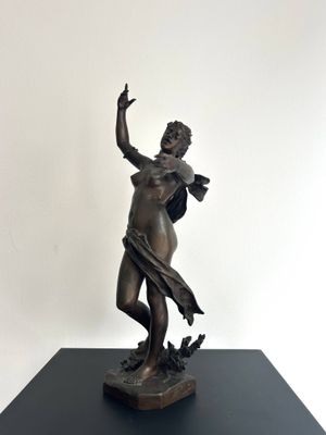 statue en bronze représentant une femme tenant un oiseau, posée sur un socle noir