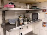 a kitchen with stainless steel counter tops and a microwave on the wall